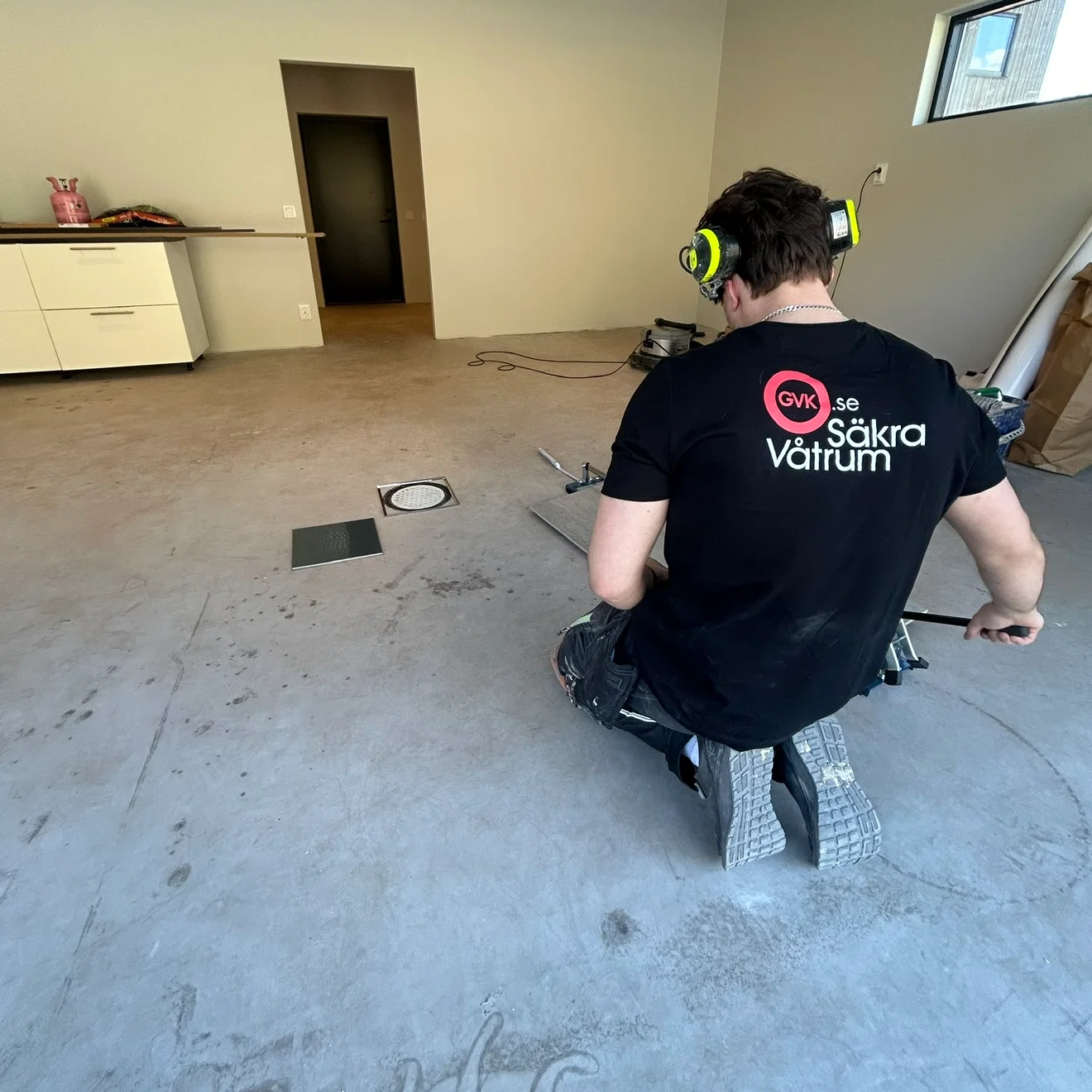 Hantverkare från NJ Bygg o Kakel med GVK Säkra Våtrum-tröja lägger klinker